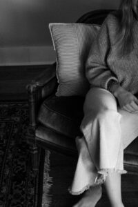 Person sitting quietly with hands resting in their lap, soft natural light, representing the mind-body connection in mental health and stress awareness